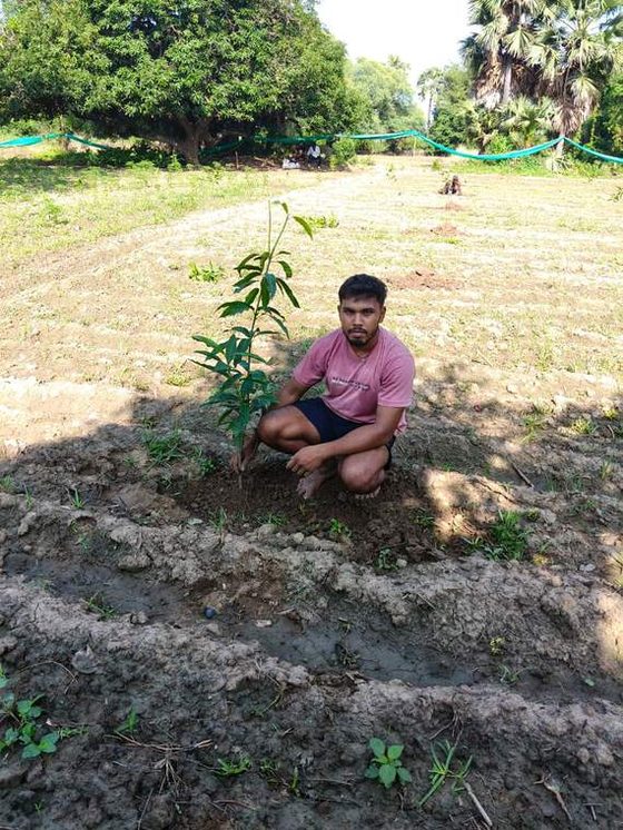 A crew member with a tree they planted for Operation Safed Sagar